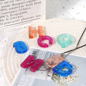 Detail of glitter-filled resin letter keychains showing colorful sequins and textures