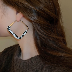 Close-up of gold-rimmed leopard print diamond earrings worn on model for a chic look