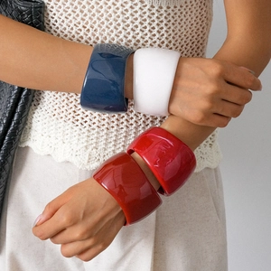 Polished resin chunky geometric bracelets in navy blue, white, and red on female model