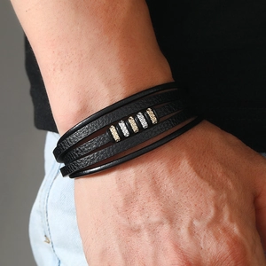 Detail of multi-layer black leather bracelet with silver and gold metal beads on wrist