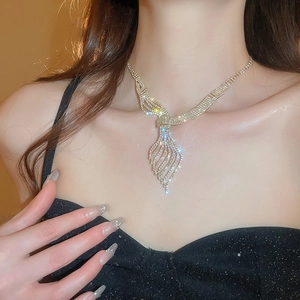 Close-up of elegant gold leaf necklace with rhinestones worn by a model in warm light