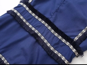 Gros plan détaillé de la robe bleu marine avec bordure géométrique et franges décoratives
