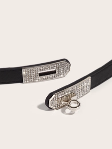 Close-up of black leather belt featuring a silver turn-lock buckle with crystal rhinestones