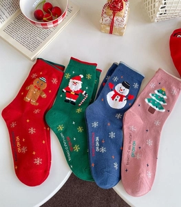 Flat lay of four colorful Christmas socks featuring holiday characters and festive text