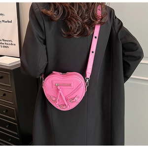 Détail du sac à bandoulière rose en forme de cœur avec rivets et franges en cuir