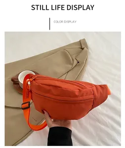 Detailed close-up of orange nylon belt bag with adjustable strap in casual outdoor setting