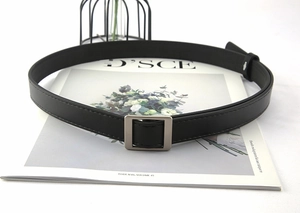 Detail of a black faux leather belt featuring a silver square buckle and stitched edges