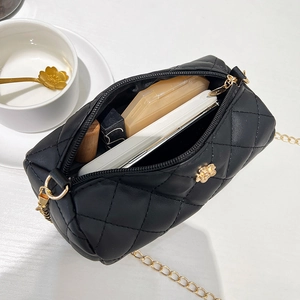 Quilted black cylinder crossbody bag with gold chain showing internal storage capacity