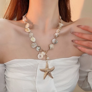 Detail of beaded necklace with starfish charm and pearls on model neck in soft light