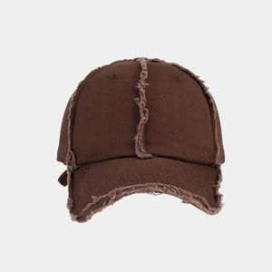 Close-up of distressed cotton baseball cap featuring raw edge fringe and vintage brown texture