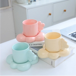 Ceramic mugs with chubby handles and petal saucers in pink, yellow, and mint green