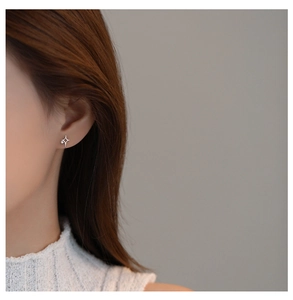 Close-up of star-shaped silver stud earring with zircon on a model for a minimalist look