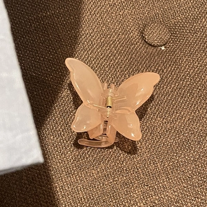 Detail of a light pink translucent butterfly hair claw clip with a gold metal spring
