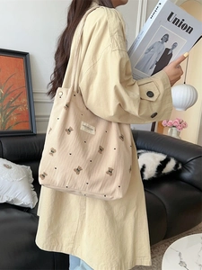 Corduroy tote bag with cartoon bear print shown in a lifestyle setting with beige trench coat