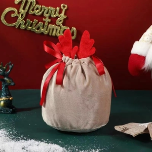 Close-up of velvet Christmas reindeer gift bag with red antlers and drawstring closure