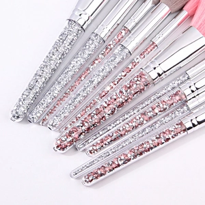 Detail of diamond handle makeup brushes with silver and pink crystals in transparent tubes
