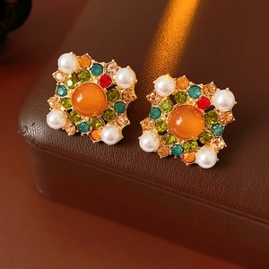 Gros plan sur des boucles d'oreilles vintage dorées avec pierres orange et strass colorés