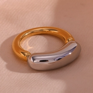 Detailed close-up of a dual-tone 18K gold and silver plated titanium steel ring on pink fabric