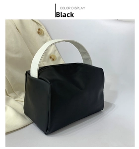 Close-up of black crossbody bag with textured fabric and white woven handle
