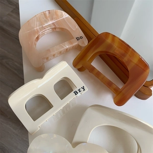 Minimalist geometric D and B letter acetate hair claws in tortoise shell and cream colors