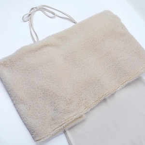 Dettaglio dell'abito a fascia in ecopelliccia beige con lacci e consistenza morbida