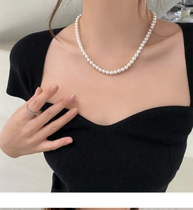 Gros plan d'un collier de perles blanches élégant sur un mannequin en haut noir