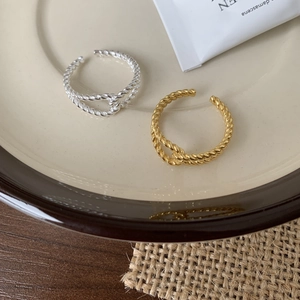 Detailed close-up of gold and silver twisted rope rings on a ceramic plate