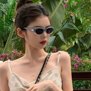 Vintage-Sonnenbrille mit ovalem grauem Farbverlaufsrahmen, getragen von einem Model im Garten