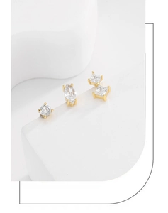 Macro view of geometric gold earrings set with sparkling marquise and round zircon stones