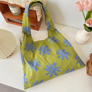 Artistic blue flower canvas tote bag displayed in a cozy home setting with tulips