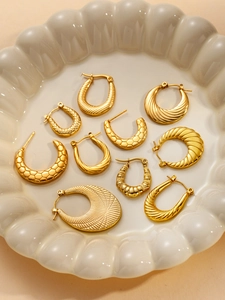 Detailed close-up of textured gold hoop earrings with honeycomb and spiral patterns
