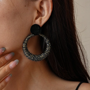 Close-up of vintage black flocked hoop earring with gold sparkle on a model's ear