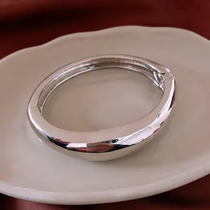 Bracelet jonc minimaliste en métal argenté poli sur une assiette en céramique