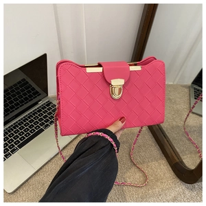 Detail of the hot pink woven texture and gold metal chain strap of the shoulder bag