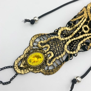 Close-up of black gothic lace hand chain with golden metal and yellow gemstone