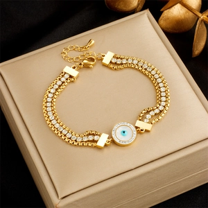 Detail of gold multi-layer bracelet with sparkling zircons and blue evil eye charm