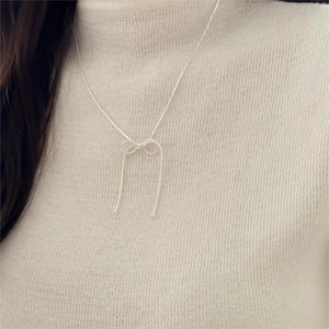 Minimalist 925 sterling silver bow necklace with elegant tassel pendant on model