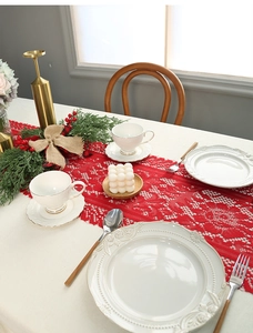 Close-up of red lace Christmas table runner with intricate knitted patterns and elegant fringe