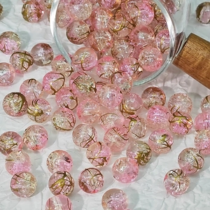 Detailed macro view of 10mm pink and gold cracked pattern glass beads for jewelry making