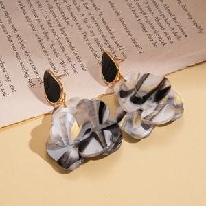 Détails de boucles d'oreilles fleurs en résine marbrée avec textures dorées et clous noirs