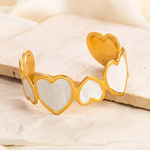 Detailed macro of gold heart bangle with white marble enamel on stone background