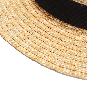 Detailed close-up of tight spiral wheat straw weave and black satin ribbon decoration