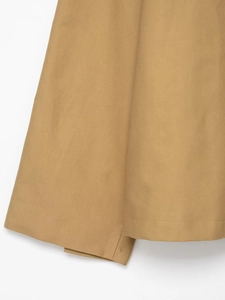 Macro detail of khaki twill fabric with precision stitching on a women's short trench coat