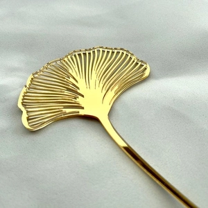 Detailed close-up of golden ginkgo leaf acrylic cake topper with fine hollowed design