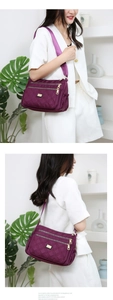 Detail of purple quilted oxford crossbody bag with multiple gold zippers and strap