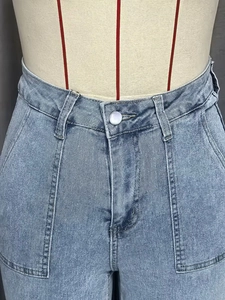 Detailopname van een high-waist spijkerbroek met metalen knoop en verfijnde zakstiksels