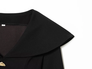 Close-up of elegant black top neckline featuring wide lapels and a gold button detail