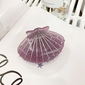 Détail macro d'une pince à cheveux coquillage violette avec paillettes et strass