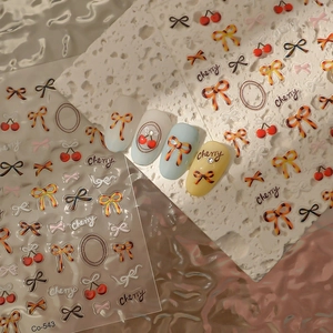 Detail of 3D embossed nail stickers featuring leopard bows and cherry patterns