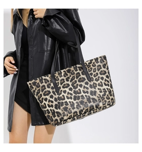 Detail shot of leopard print tote bag featuring black leather straps and textured material